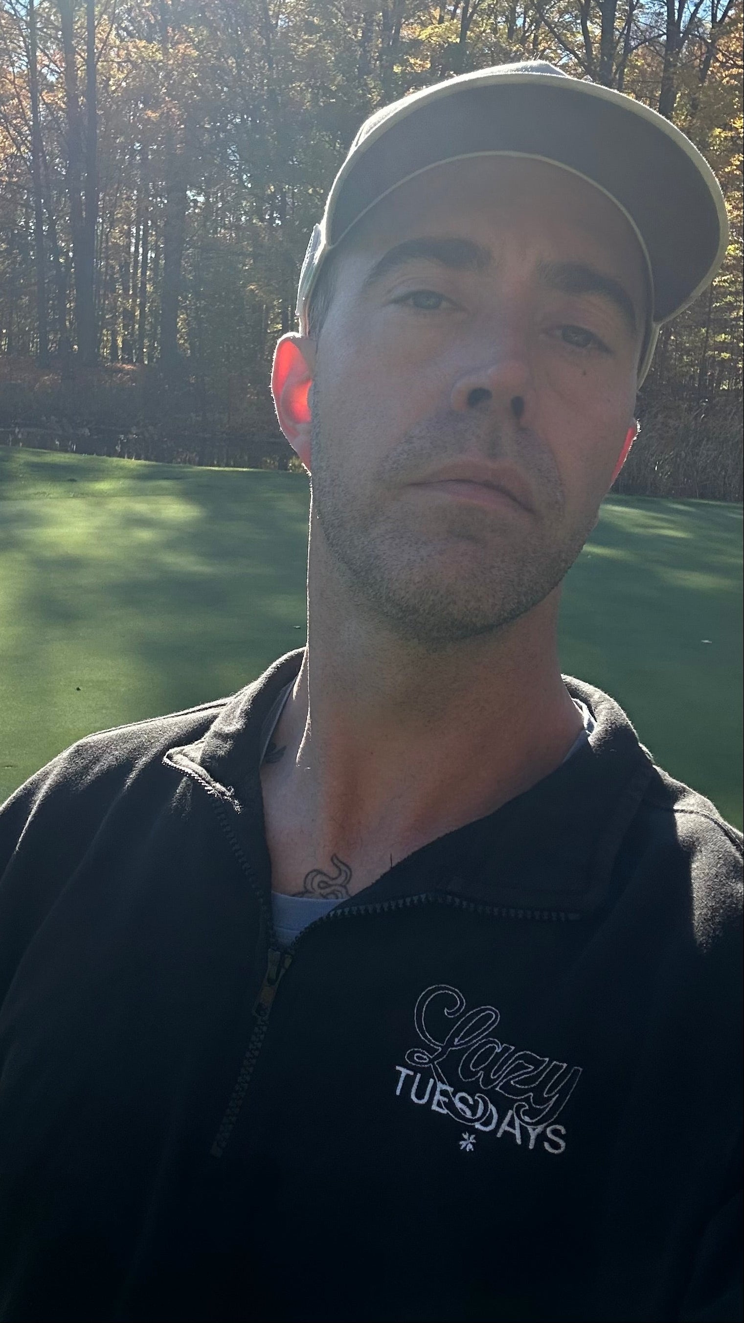 Man wearing a black hoodie with text in an outdoor setting